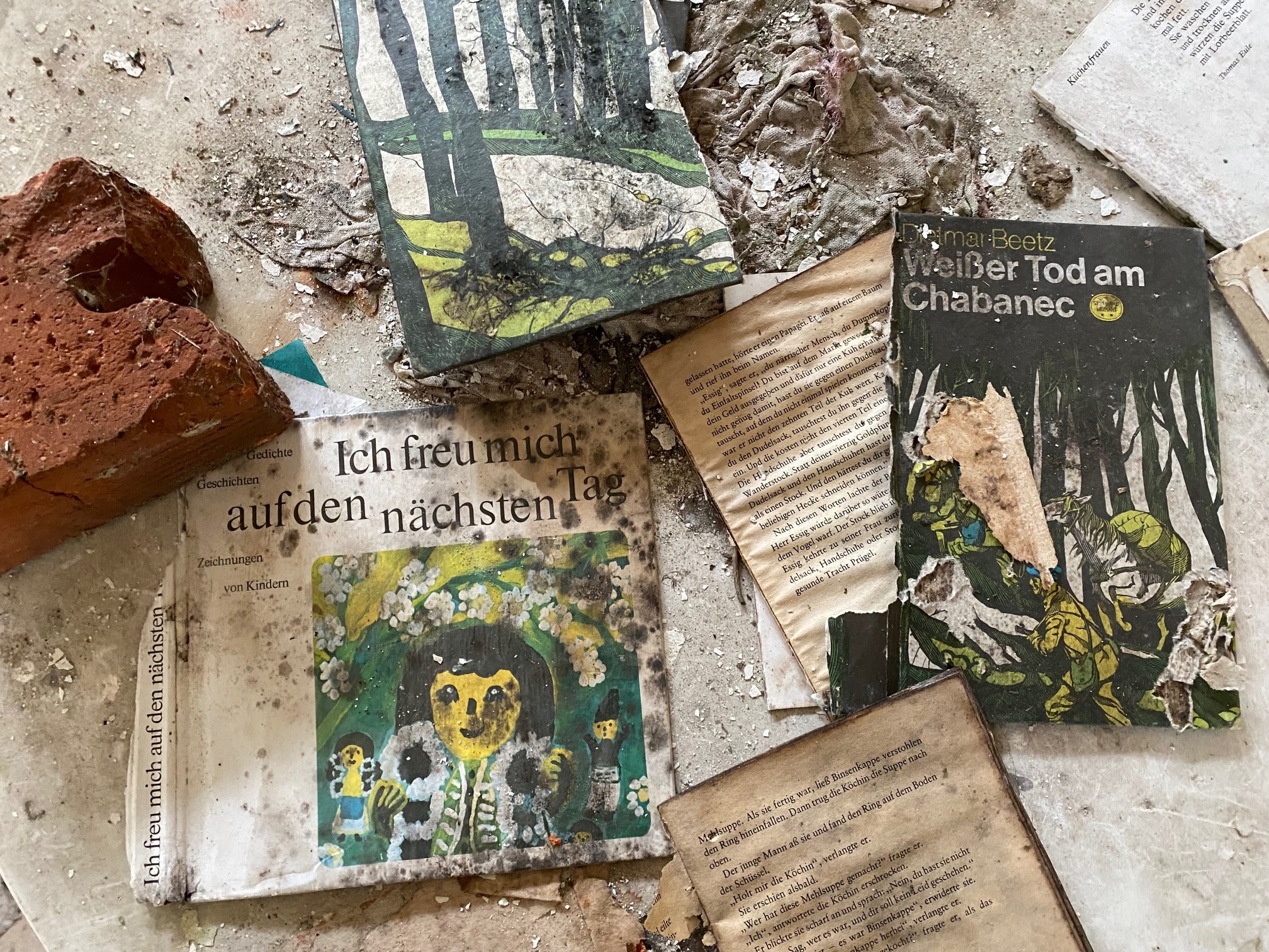 Zerfallende Kinderbücher auf einem staubigen Boden