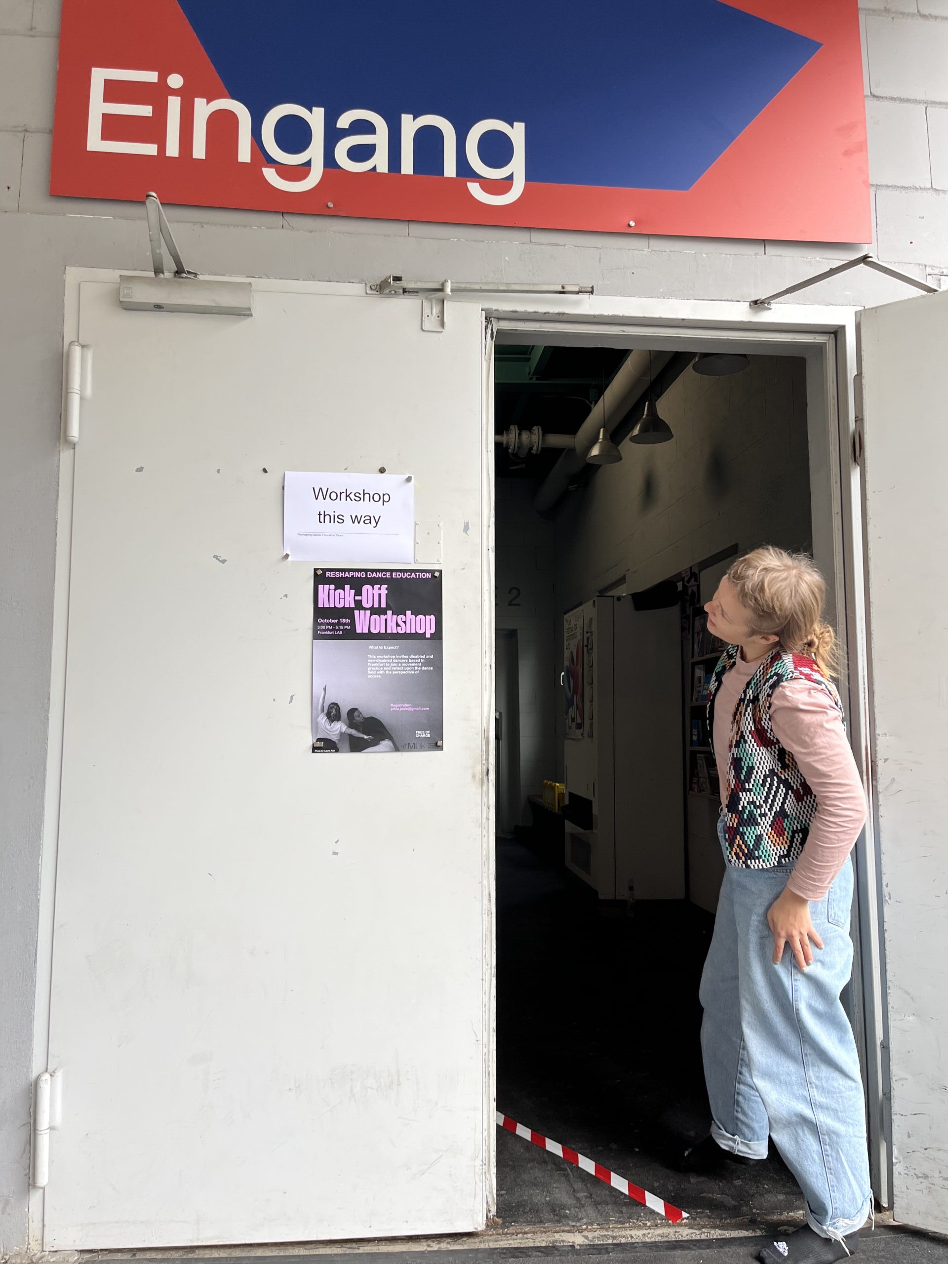 Eine Person steht seitwärts im Eingang des Frankfurt LAB und betrachtet ein Plakat mit der Aufschrift Kick-Off Workshop