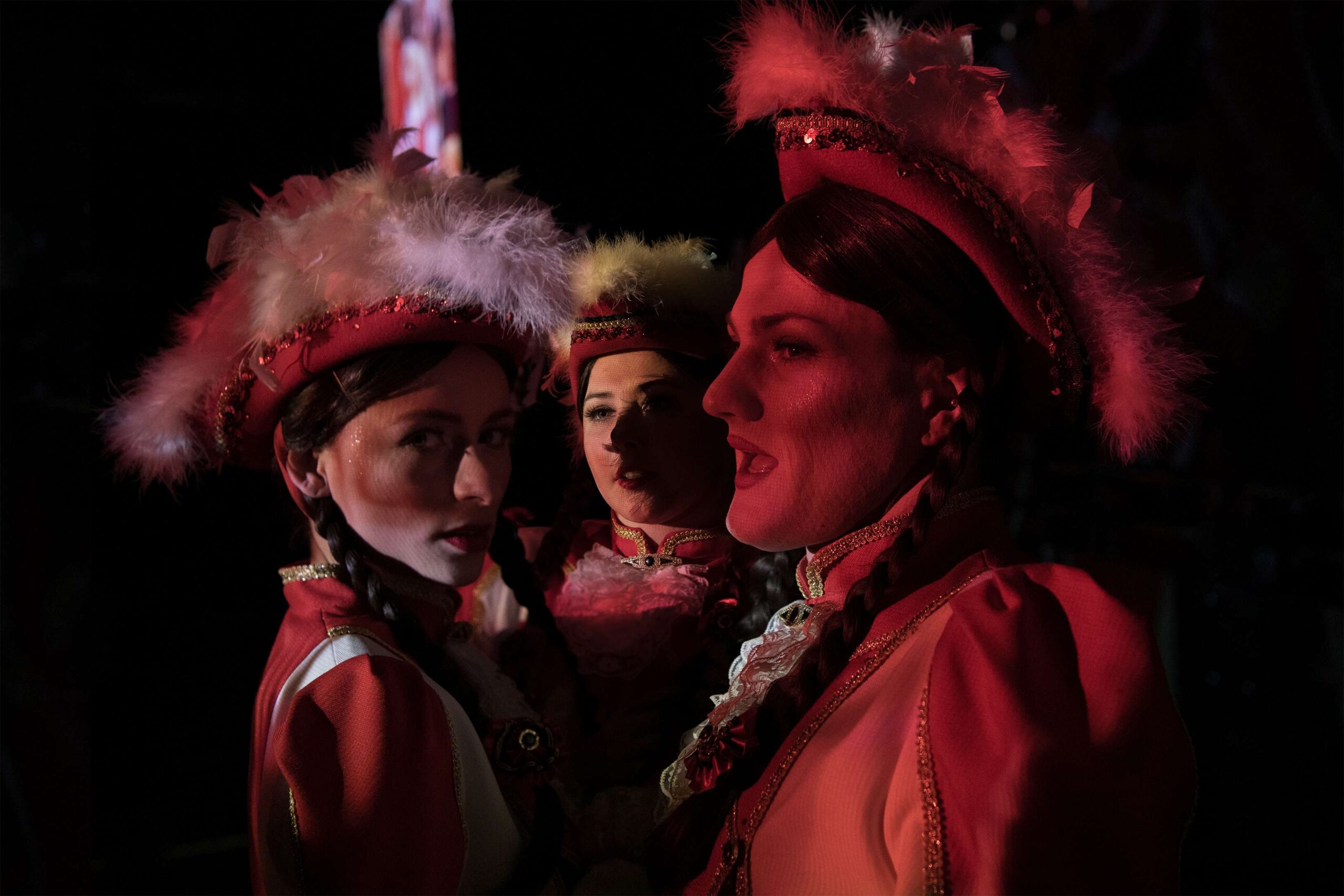 Three women with braids and carnival hats and uniforms.