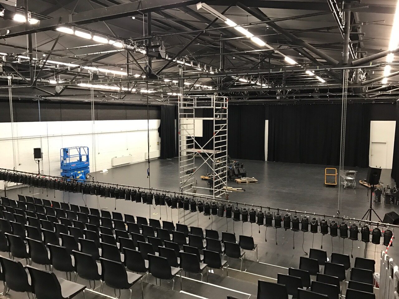 Die Halle 1 ist bei Aufbauarbeiten zu sehen. Auf der Bühne stehen viele Scheinwerfer und ein Gerüst.