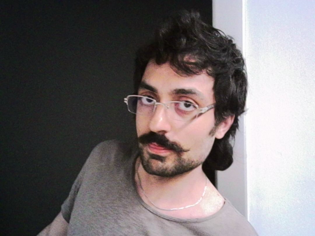 Ein Mann mit Brille und Bart lehnt sich ins Bild.