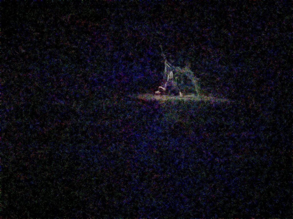 Verschwommenes Schwarz mit farbiger Struktur, weit hinten im Bild liegt eine Person auf dem Boden in einem Lichtkegel.