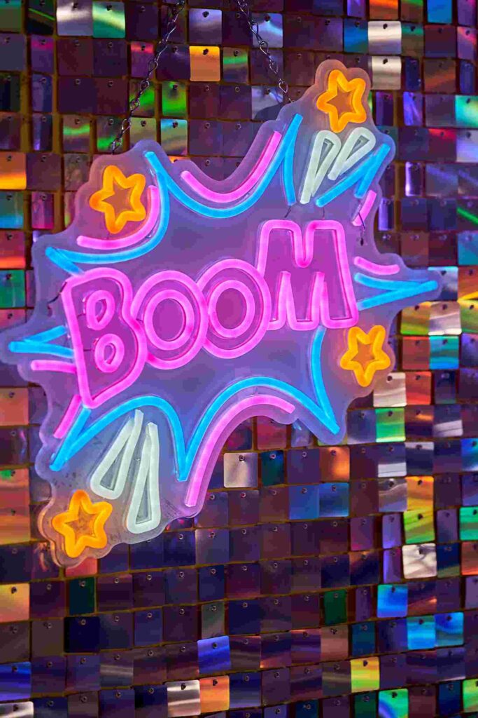 Ein Foto einer Neonleuchtschrift an einer Wand. Zu lesen ist "Boom", geschrieben wie in einem Comic