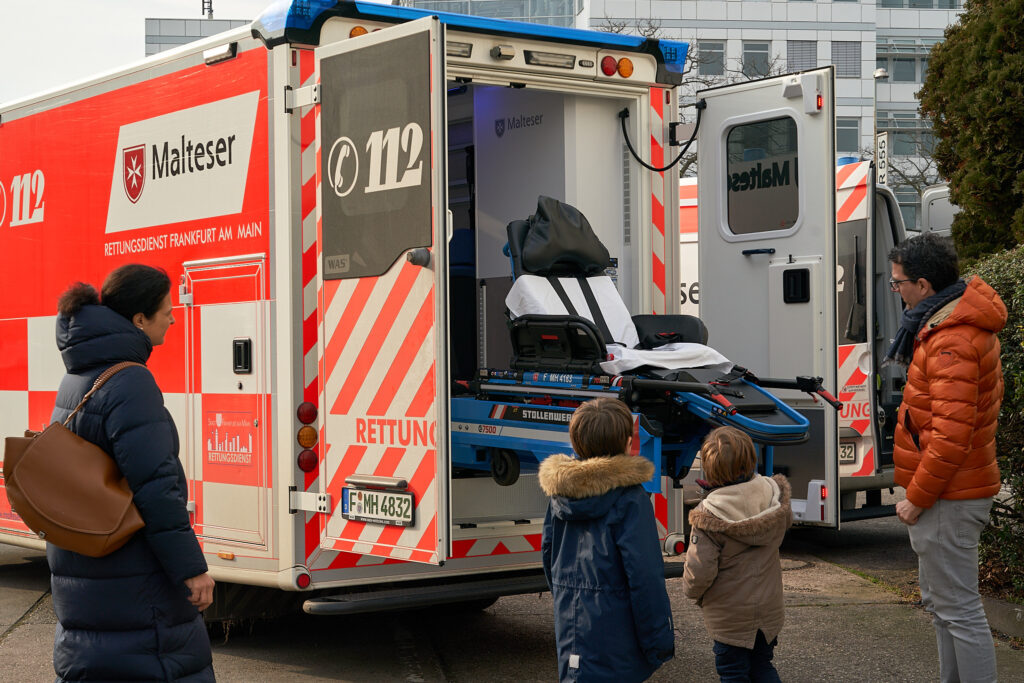 Foto eines offenen Krankenwagens der von Kindern besichtigt wird.